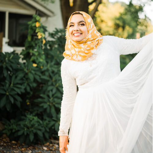 A Pakistani woman with a hijab smiles at the camera.